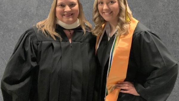 Daughter in graduation cap and gown with her mother in cap and gown